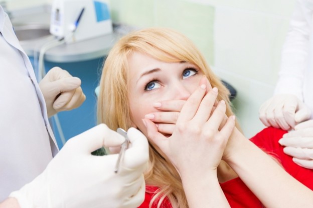 efrver Patient covering her mouth while sitting in a dental chair, illustrating how to get rid of gag reflex concerns during dental treatment and impressions.