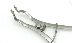efrver Rubber dam forceps used to open and position a clamp on the anchor tooth during isolation.