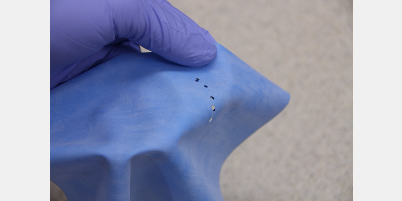 Rubber Dam Armamentarium: Tools and Techniques Guide Close-up of a rubber dam with correctly punched holes prepared for tooth isolation during a restorative dental procedure.
