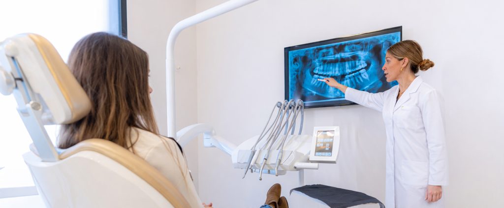 Treatment planning for new dentists reviewing panoramic radiograph with patient