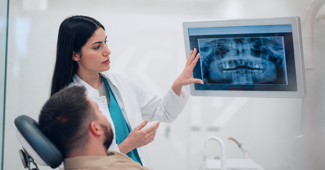 Doctor Development in DSOs: The Missing Link Dentist reviewing digital X-rays with a patient as part of structured doctor development in DSOs focused on clinical communication and treatment planning.