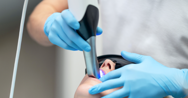 Dental clinician using an intraoral scanner during a patient exam as part of a DSO technology strategy focused on clinical consistency, efficiency, and digital workflows.