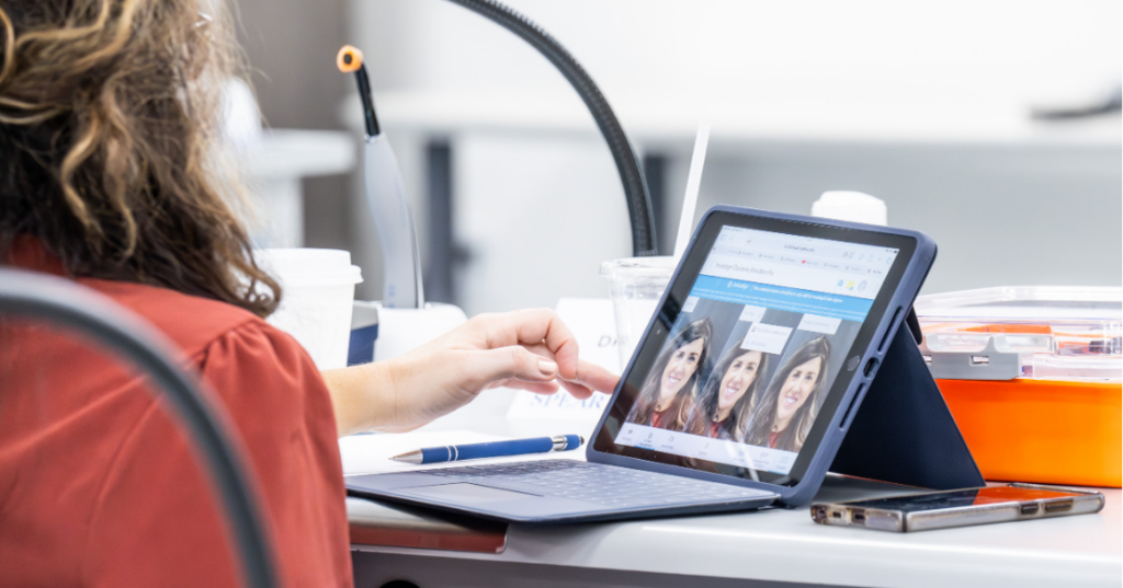 AI in Dental Diagnostics for Stronger Case Acceptance Dental team member reviewing an AI in dental diagnostics outcome simulation of a patient on a tablet.