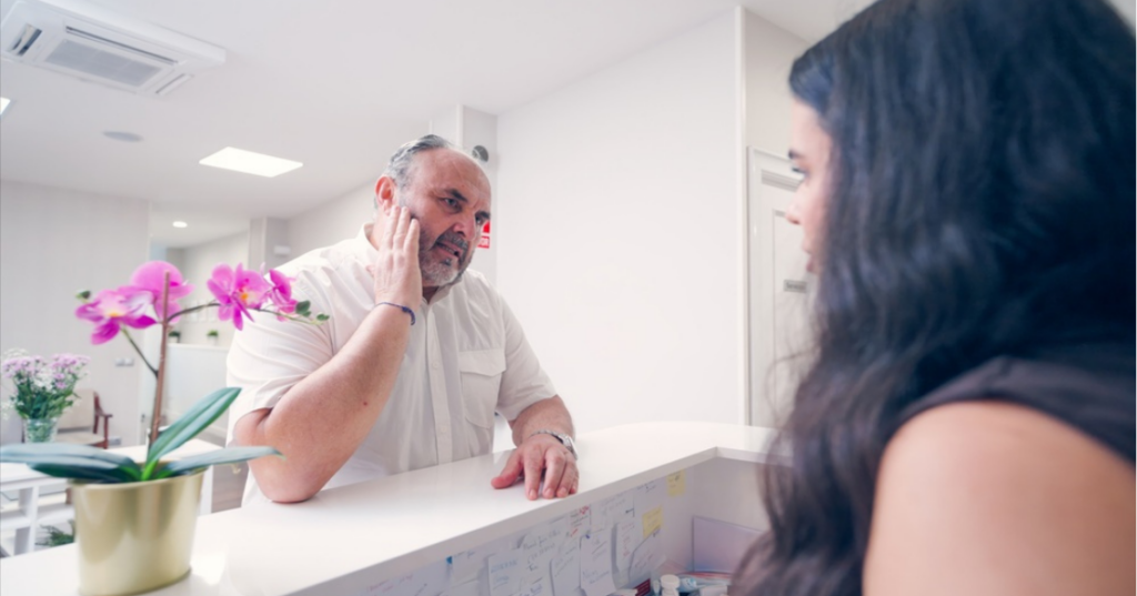 Front desk staff managing endodontic emergencies as a patient in pain describes his symptoms during a walk-in visit.